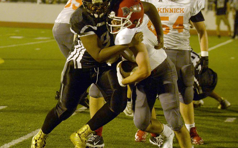 Zama's Tim Armstrong wraps up Nile C. Kinnick running back Kaito DeMoss.