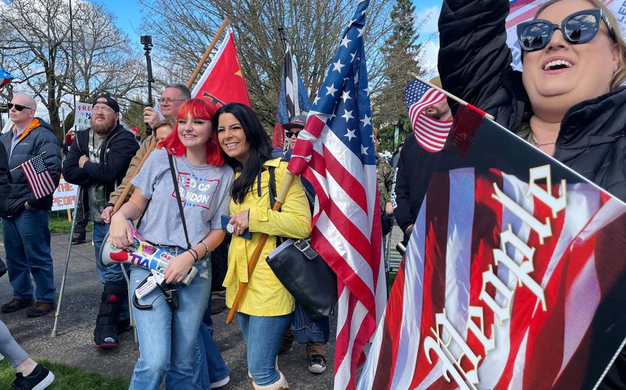 Melanie Gabriel, left, pictured with her bullhorn, is a 14-year-old anti-mandate activist from Washington state. She poses for photos with supporters after a speech at the state Capitol in Olympia on March 5, 2022.