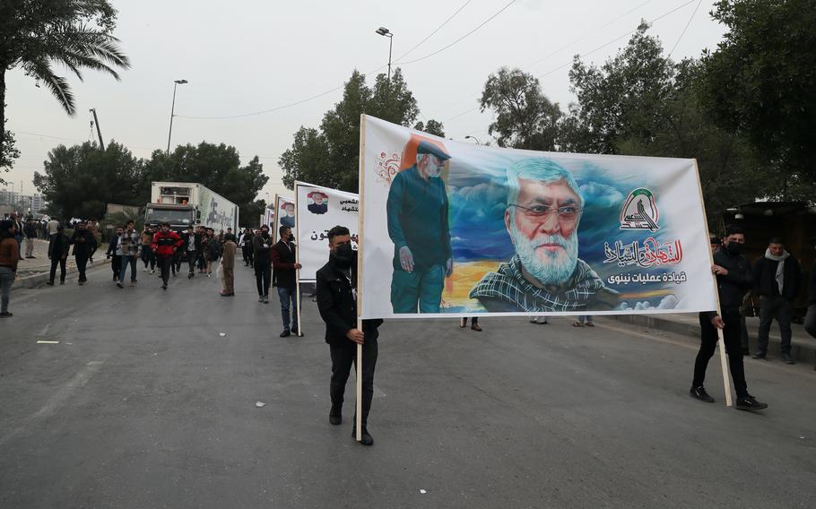 Supporters and members of the Popular Mobilization Forces hold posters of a powerful Iranian general and a top Iraqi militia leader in Baghdad, Iraq, Saturday, Jan. 1, 2022. Hundreds rally in Baghdad on Soleimani assassination anniversary, chanting anti-American slogans, hundreds of people rallied in in the Iraqi capital on the first day of the year Saturday to mark the anniversary of the killing of a powerful Iranian general and a top Iraqi militia leader in a U.S. drone strike. (AP Photo/Khalid Mohammed)