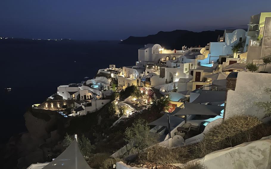 The blue lights of infinity pools and jacuzzis of luxurious hotels illuminate the village of Oia, on the island of Santorini, Greece, on Sept. 3, 2021. Oia is the ritziest of the villages carved into the rim of the island volcano that exploded into the sea 3,600 years ago.