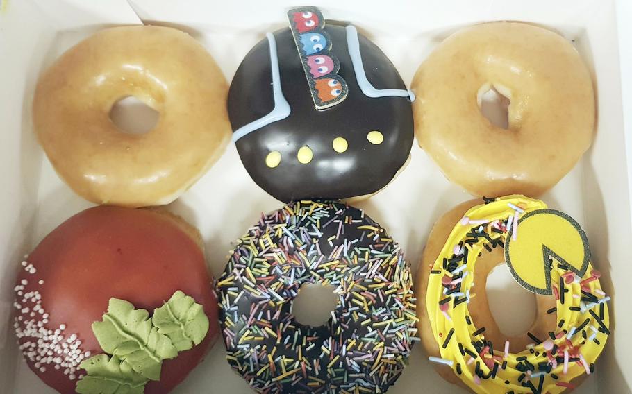 A close-up view of a box with six doughnuts of varying colors.