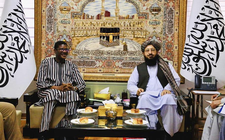 Two men in traditional dress sit in next to each other.