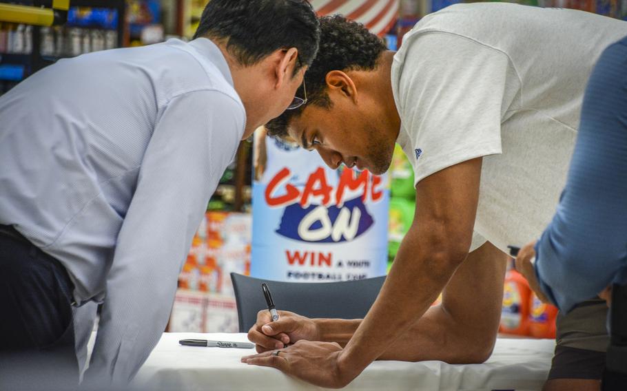 Baltimore Ravens strong safety Kyle Hamilton signs an autograph for a fan in the commissary at Camp Humphreys, South Korea, April 12, 2024.