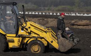Workers ride by an excavator to construct new defensive positions close to the Russian border in the Kharkiv region, Ukraine, on Wednesday, April 17, 2024.