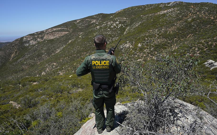 A U.S. Border Patrol agent calls for fellow agents on a radio in the area at Otay Mountain on June 8, 2021. 