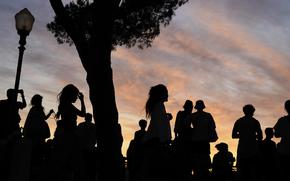 People stand in shadows as the sun sets.