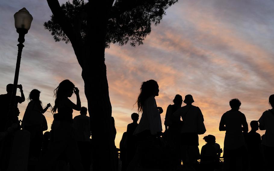 People stand in shadows as the sun sets.