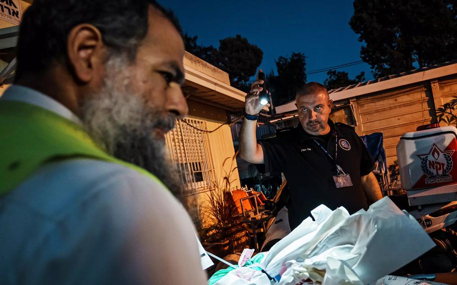 Yohanan Eynee, left, and Eli Horen, a police officer, move bags that arrived from the Shura military base in Israel.