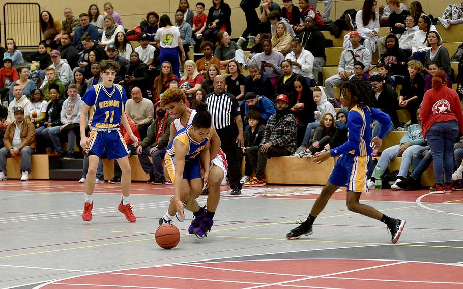 Wiesbaden's Nigel Rodriquez and Kaiserslautern's Tyriq Etan fight for the ball during Friday evening's game at Kaiserslautern High School in Kaiserslautern, Germany. Watching the action are the Warriors' Gavin DeLuca and Jordan Thibodeaux.