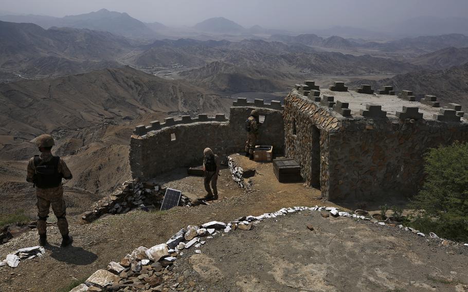 In this Aug. 3, 2021 file photo, Pakistan Army troops observe the area from hilltop post on the Pakistan-Afghanistan border, in Khyber district, Pakistan. Militants targeted an army post in Pakistan’s northwestern tribal belt near the Afghan border, killing a soldier in a firefight overnight, Pakistan’s military said. 