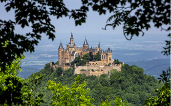  Burg Hohenzollern on a sunny day framed by the shadow of tree leaves