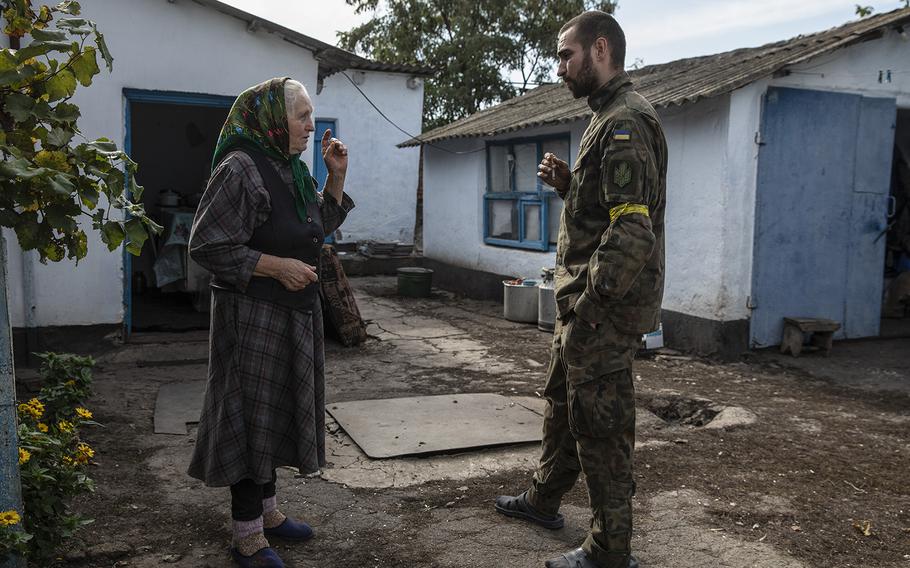 Valentyna, 70, speaks with a soldier who goes by the call sign Porokh and is sleeping along with other soldiers in her home in the Kherson region. 