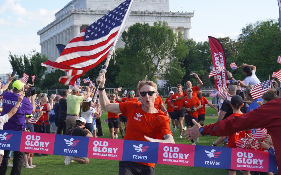 A runner crosses the finish line with the American flag in hand