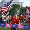 A runner crosses the finish line with the American flag in hand