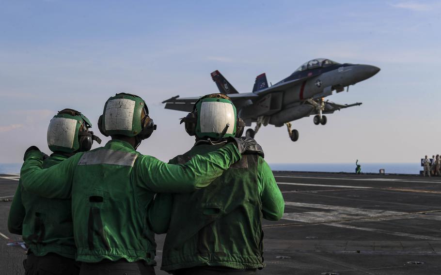 Sailors watch a Navy fighter land on the aircraft carrier USS Abraham Lincoln in the South China Sea on March 23, 2022. 