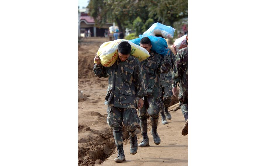 Members of the Armed Forces of the Philippines carry bags of aid and rice transported by U.S. military helicopters to assist relief efforts in storm-ravaged areas in the Philippines.