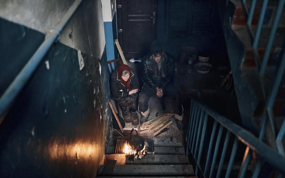 Local residents cook on the stairs of an apartment house in Chasiv Yar, Donetsk region, Ukraine, Monday, March 6, 2023. 