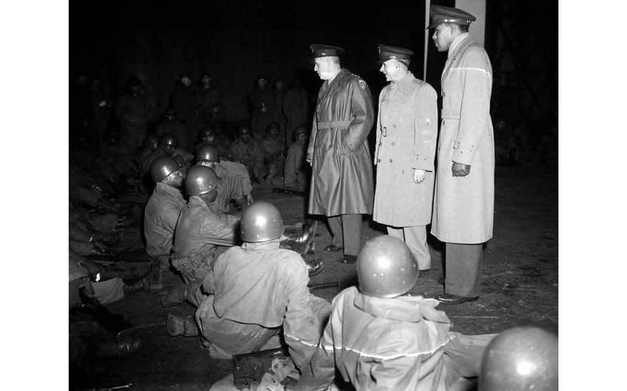 Lt. Gen. Clarence R. Huebner (left) talks to some of the soldier-students at the Kitzingen Basic Training Center for Negro troops, accompanied by Brig. Gen. Lewis C. Beebe, commandant of the center (center) and Lt. Col. Marcus Ray, EUCOM adviser on Negro affairs (right). 