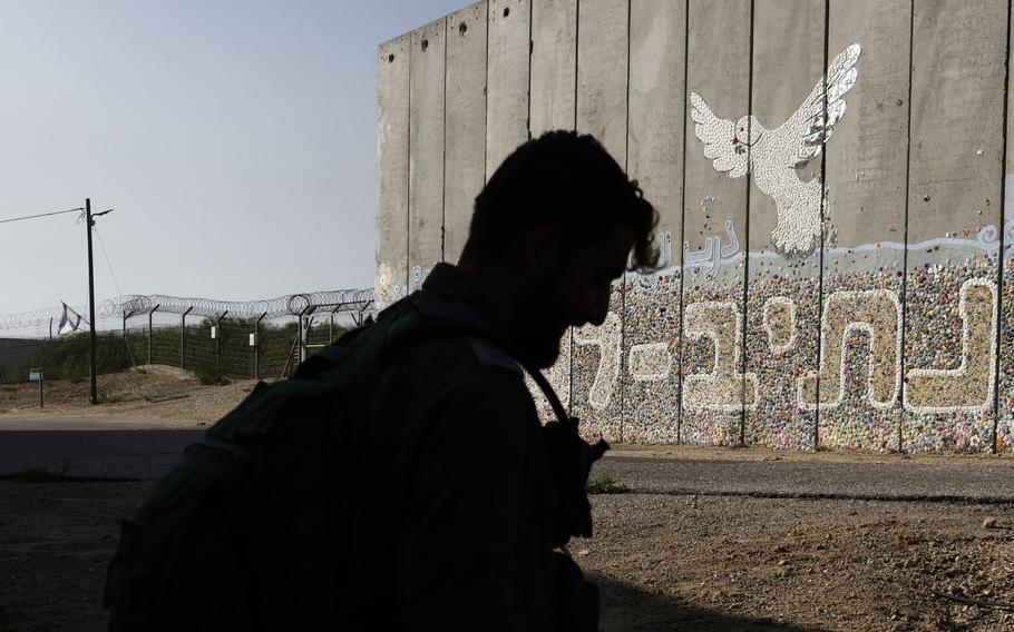 An Israeli soldier patrols at a protective security barrier decorated with the “Path for Peace” mural at the border fence with the Gaza Strip in southern Israel, on Nov. 17, 2023.
