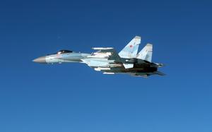 A Russian military fighter jet, seen from the side, flies through open air space.