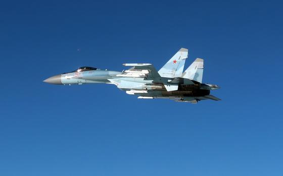 A Russian military fighter jet, seen from the side, flies through open air space.