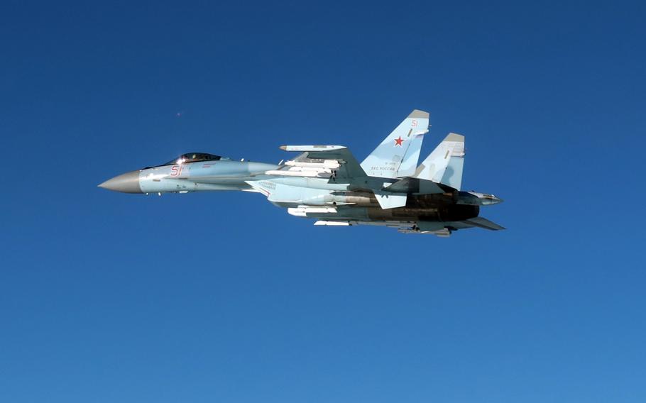 A Russian military fighter jet, seen from the side, flies through open air space.