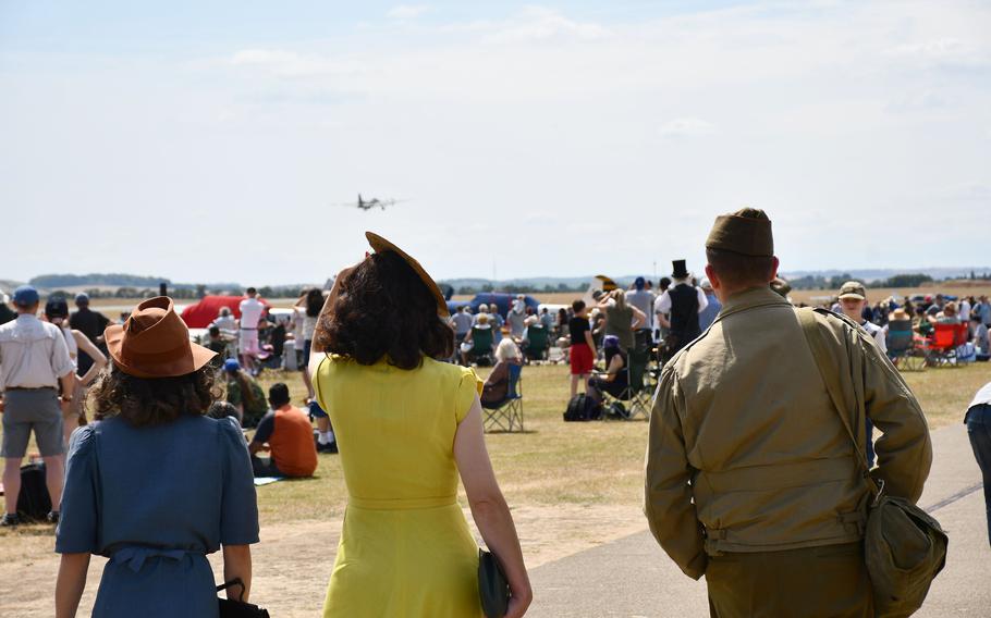 Visitors dressed in WWII-era attire watch as the B-17, the Sally B, takes off the runway at the Duxford Air Show. 