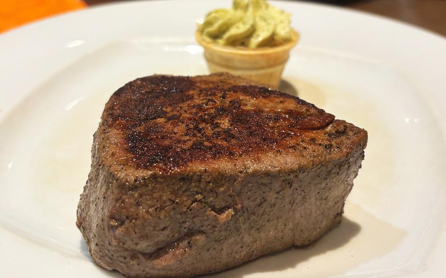 Filet mignon on a white plate with herb butter.