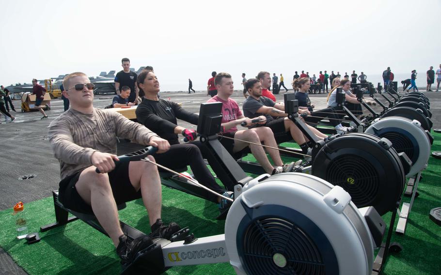Sailors use rowing machines during a run and row event on the flight deck of the aircraft carrier USS Harry S. Truman in the Adriatic Sea, March 27, 2022. Defense Secretary Lloyd Austin has extended the Truman carrier strike group's deployment to the 6th Fleet area of operations.