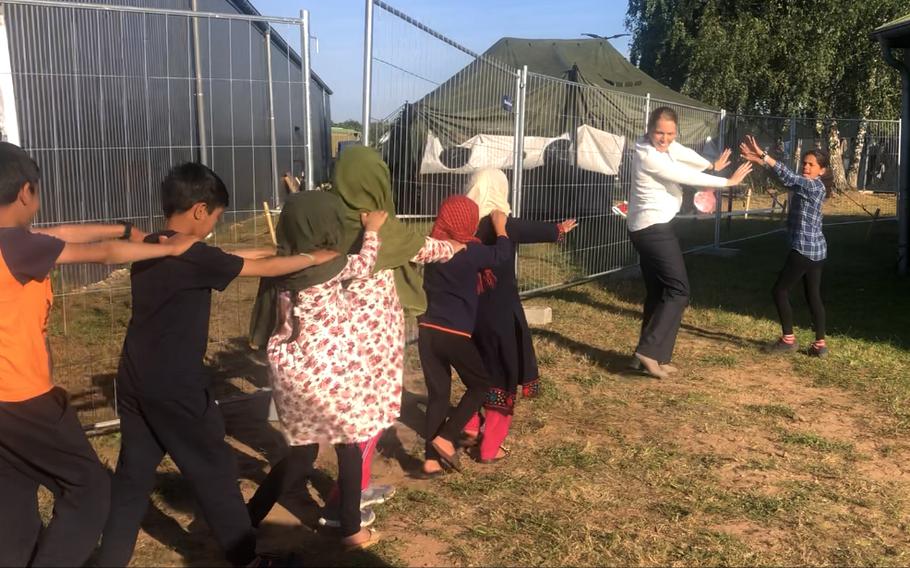 Volunteer teacher Morgan Guinn, second from right, and one of her Afghan students, Heri, right, lead other evacuee children to an Army tent on Rhine Ordnance Barracks for English lessons, Sept. 23, 2021.  