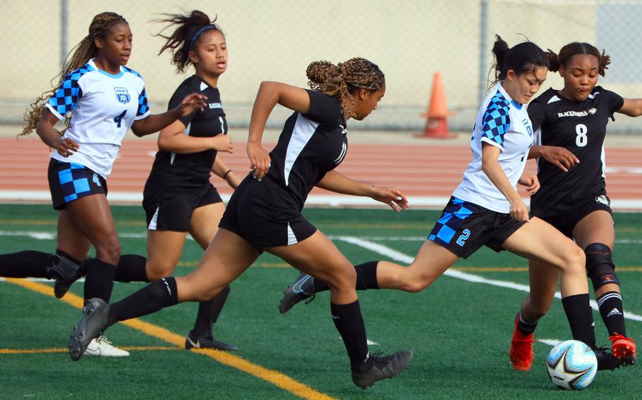 Osan's Vivian Machmer dribbles the ball through Humphreys opponents Syra Soto, Lailah Anderson and Christine Sanchez with Cougars teammate Tatiana Lunn in trail during Friday's Korea girls soccer match. The Blackhawks won 5-2.
