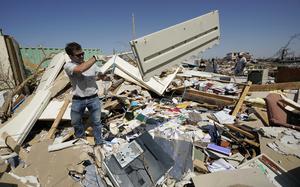 Charlie Weissinger, tosses away the paneling from one of the desks in his father's demolished law office in Rolling Fork, Miss., Saturday, March 25, 2023. Emergency officials in Mississippi say several people have been killed by tornadoes that tore through the state on Friday night, destroying buildings and knocking out power as severe weather produced hail the size of golf balls moved through several southern states. (AP Photo/Rogelio V. Solis)