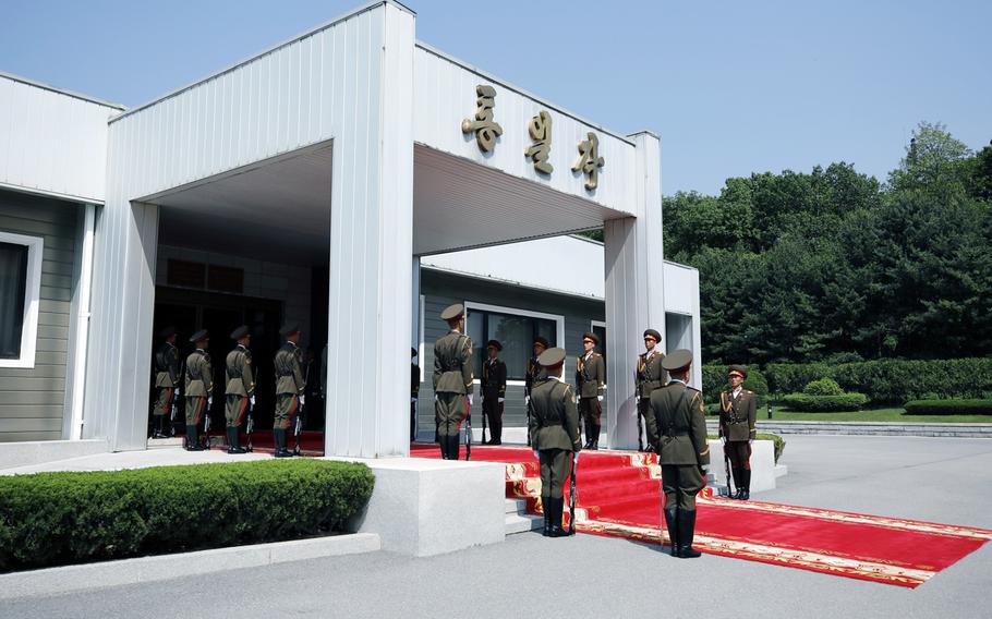  North Korean soldiers line up along a red carpet outside a conference building. 