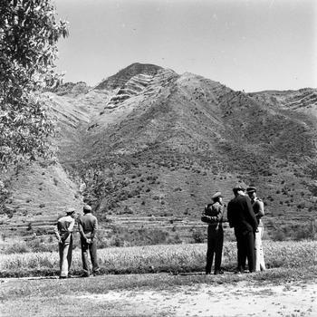 A black and white photo of security personnel in a valley with mountains behind them.