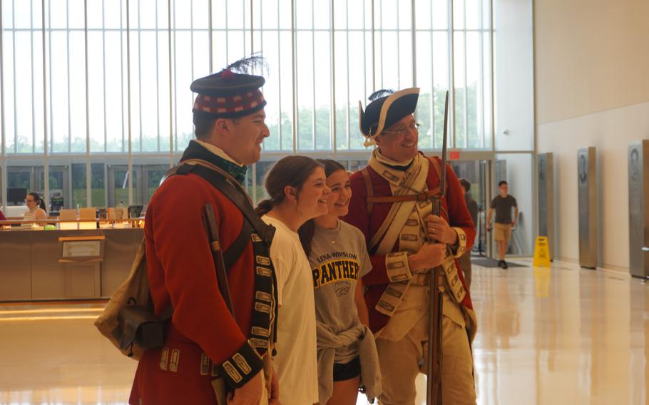 Men in Revolutionary War uniforms pose for a photo with two young girls