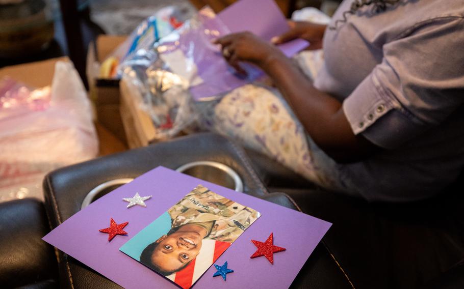 A Memorial Day card with the portrait of a female soldier on it is in-focus while a woman sits next to it, slightly out of focus.