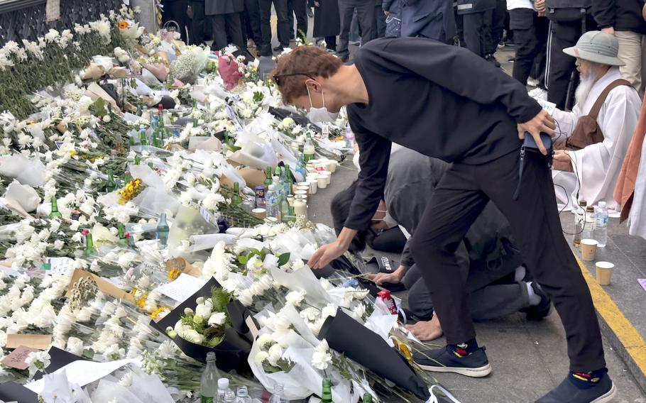 A mourner places flowers at a memorial on Oct. 31, 2022, for 156 people killed during Halloween festivities in Itaewon, South Korea. 