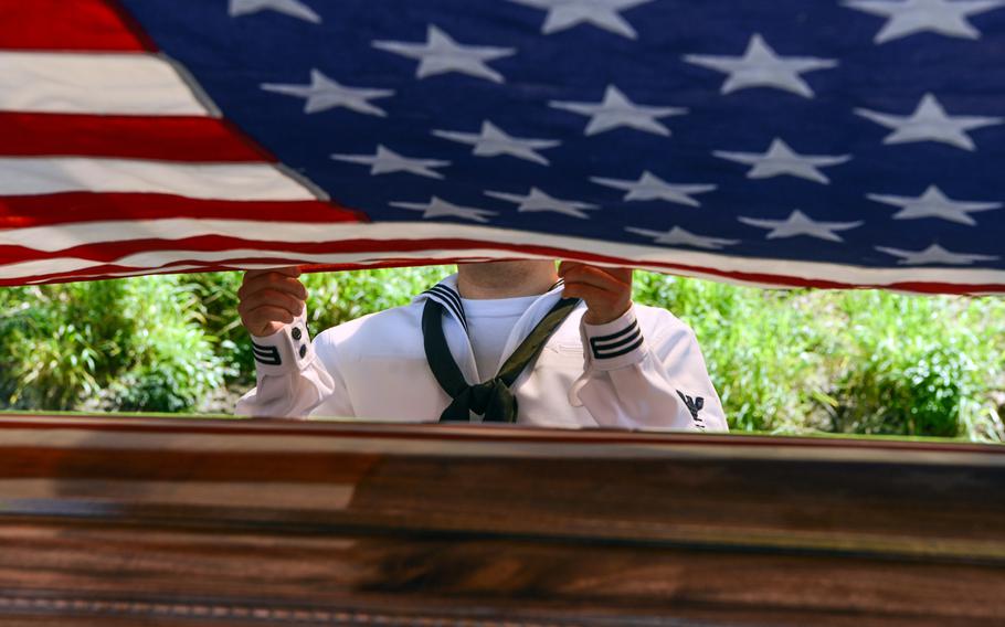 A sailor holds part of a U.S. flag during an interment ceremony for Navy Cmdr. Frederick Schrader at the National Memorial Cemetery of the Pacific in Honolulu, Hawaii, April 13, 2023. 