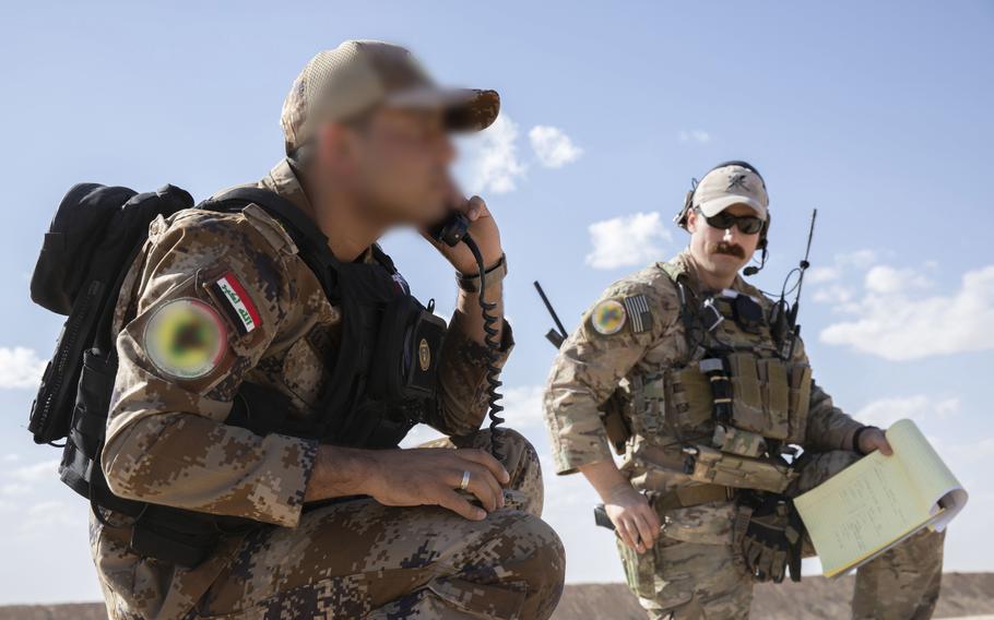 An Iraqi tactical attack controller, left, joined by a U.S. adviser, calls in an airstrike on the radio near al Asad Air Base, Iraq, Oct. 19, 2021. The image was blurred by U.S. forces to protect the Iraqi's identity. 
