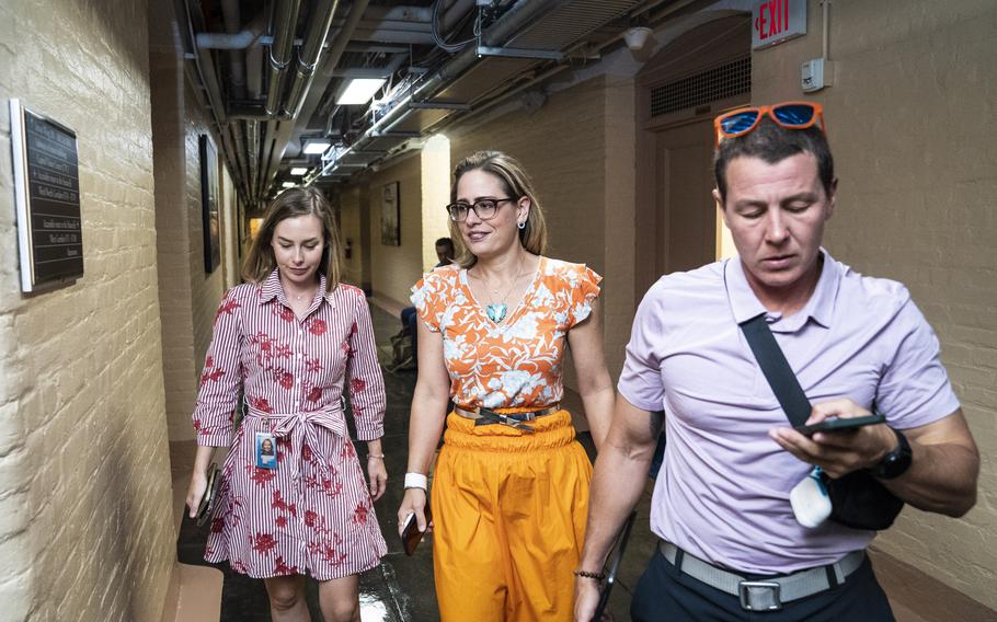 Sen. Kyrsten Sinema, center, walks to the Senate floor on Capitol Hill on Aug. 4, 2023. 