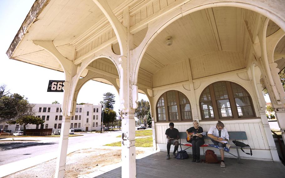 Three veterans sit on a bench outside of a historic trolley house.