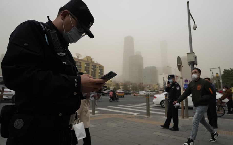Chinese police officers monitor a junction as a dust storm sweep by in Beijing, Friday, March 10, 2023. Skyscrapers disappeared into the haze and air quality plummeted as China's capital was enveloped in a dust storm and heavy pollution on Friday.