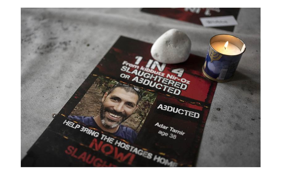 A candle burns at a Passover Seder commemoration on April 11, 2024, at the communal dining hall at Kibbutz Nir Oz in southern Israel, where a quarter of all residents were killed or captured by Hamas on Oct. 7, 2023. Tamir Adar, seen in the poster, was killed by Hamas during the Oct. 7 attack, before his body was taken to the Gaza Strip.