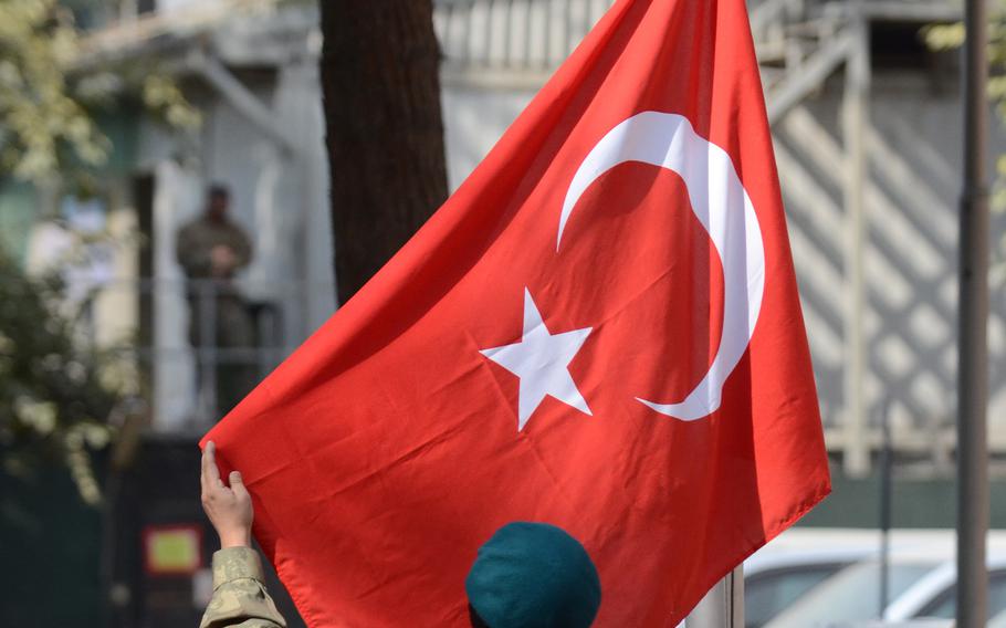 A Turkish service member adjusts the Turkish flag.