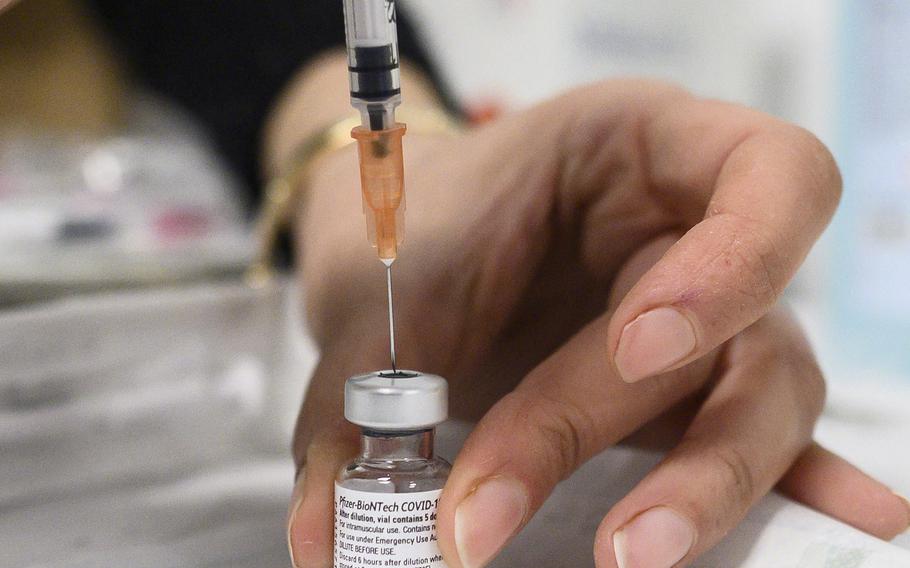 A health worker prepares a syringe with the Pfizer/BioNTech Covid-19 vaccine. Federal health officials are suggesting the surging omicron variant may cause less suffering than other strains. 