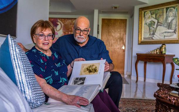 Evelyn Walg Grunberg and her son Henry Grunberg look through a family album in her apartment in Aventura. The family will gather in France this summer to commemorate Evelyns escape from Nazi Europe in 1942.