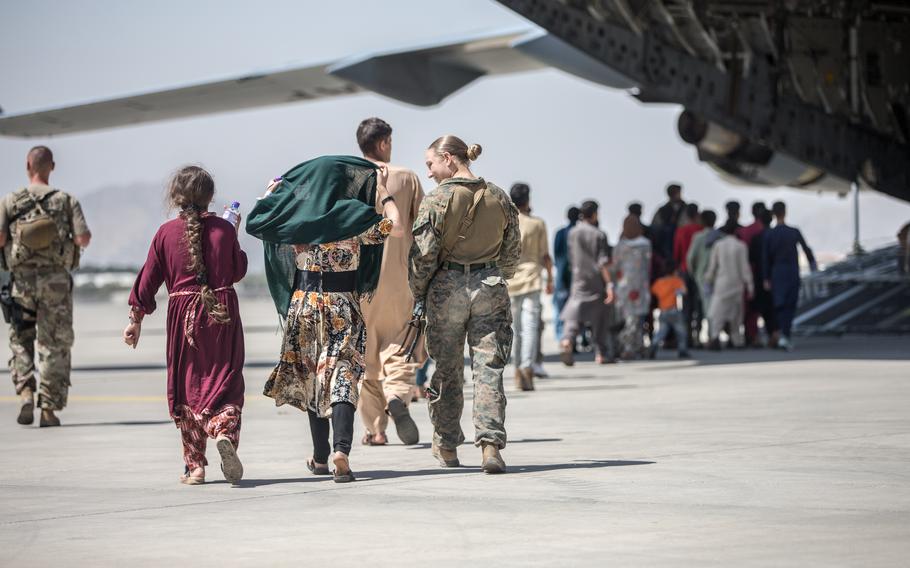 A Marine with the 24th Marine Expeditionary Unit walks with the children during an evacuation at Hamid Karzai International Airport, in Kabul, Afghanistan, on Tuesday, Aug. 24, 2021. 