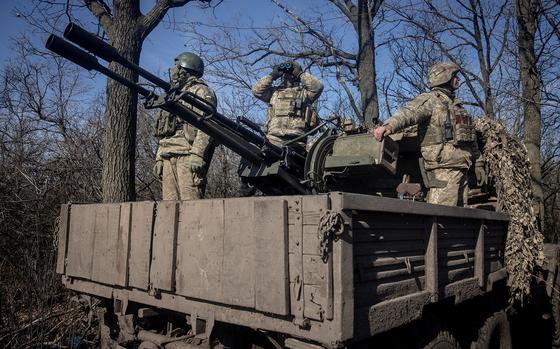 Members of Ukraine's 72nd Brigade Anti-air unit stand on the back of a ZU-23 anti-aircraft autocannon while using binoculars to search for incoming Russian drones at a frontline position on Feb. 23, 2024, near Marinka, Ukraine. (Chris McGrath/Getty Images/TNS)