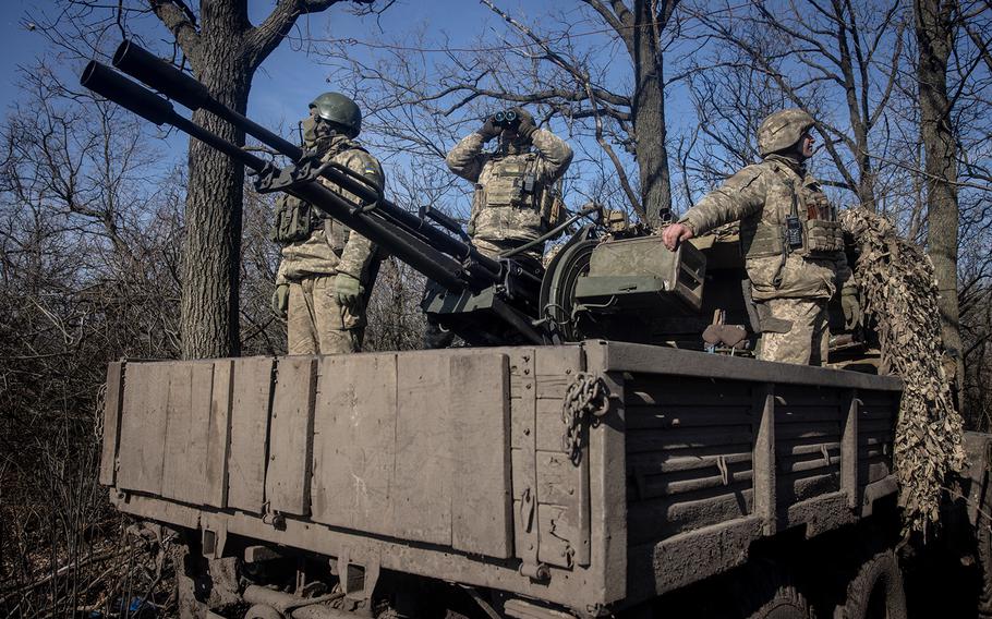 Members of Ukraine’s 72nd Brigade anti-air unit stand on the back of a ZU-23 anti-aircraft autocannon while using binoculars to search for incoming Russian drones at a front-line position on Feb. 23, 2024, near Marinka, Ukraine. 