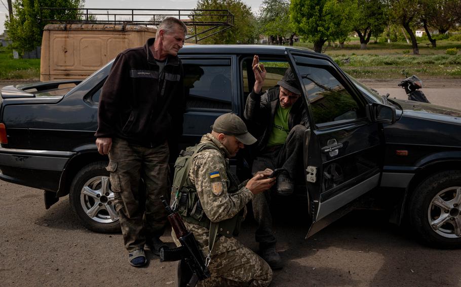 Serhiy, right, who is a farmer, waits for a food donation outside a market after he fled his village of Poltavka earlier in the day as the area came under shelling, at another village in Zaporizhzhia Oblast, Ukraine, on Wednesday, May 11, 2022.